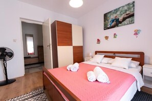 Ein Hotelzimmer mit Bett, Schrank, Nachttisch, Ventilator und einem Bild an der Wand.