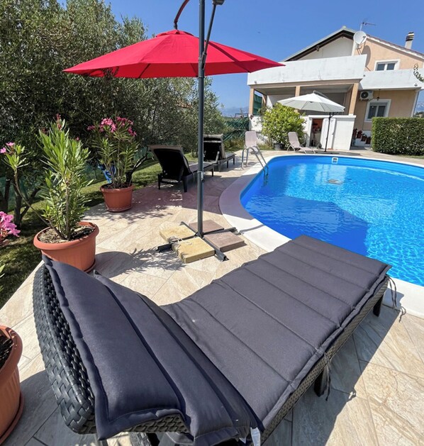 A swimming pool with lounge chairs and an umbrella. - House Bistre With Private Pool (Razanac)