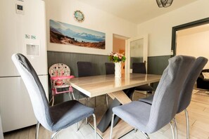 A dining area with a wooden table, grey upholstered chairs, a pink high chair, and a vase with flowers. - House Bistre With Private Pool (Razanac)