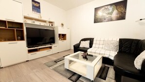 A living room with a flat-screen TV, a sofa, a coffee table, and a painting on the wall. - House Bistre With Private Pool (Razanac)