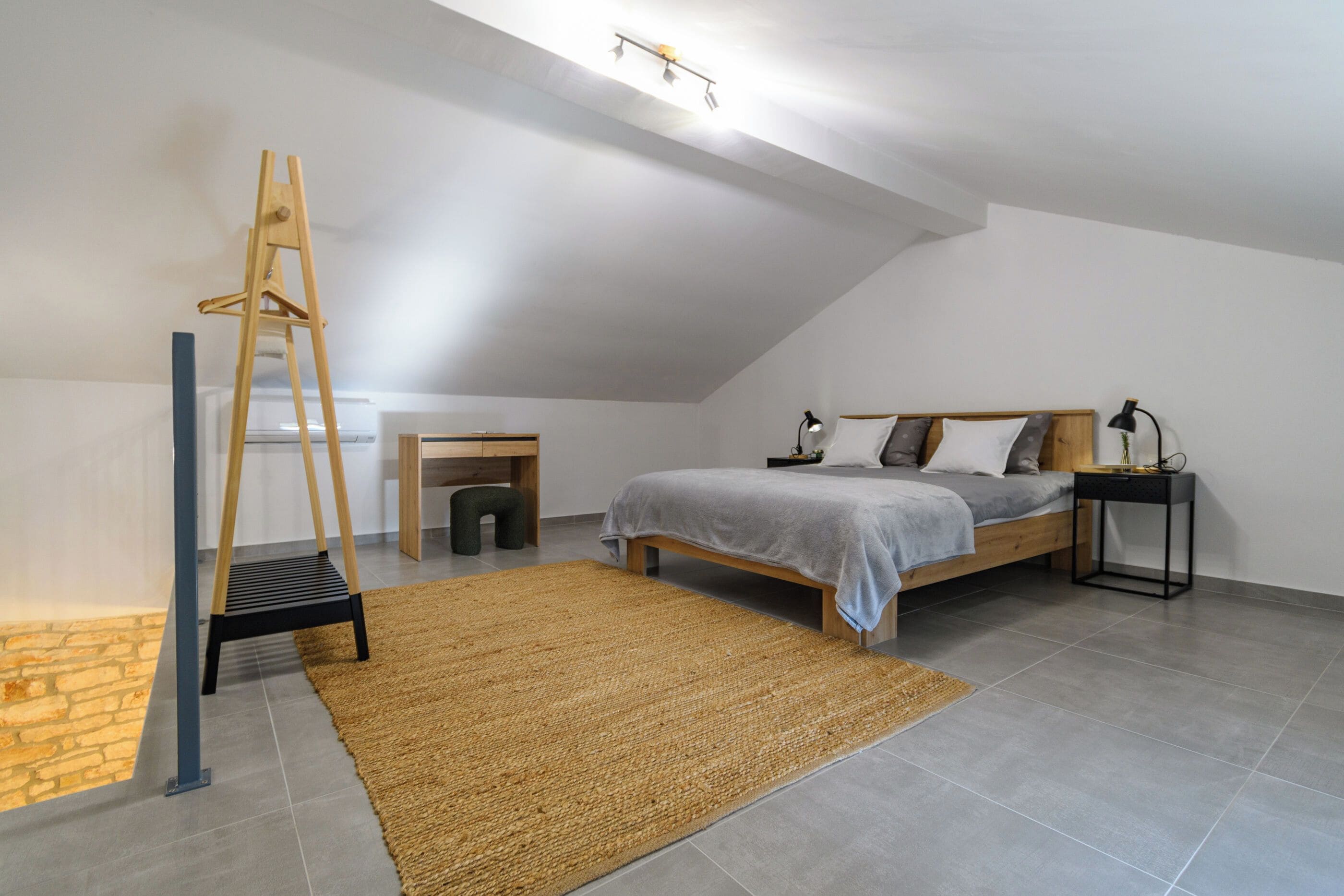 Un dormitorio con cama estilo loft, un escritorio, una escalera y una mesita de noche.