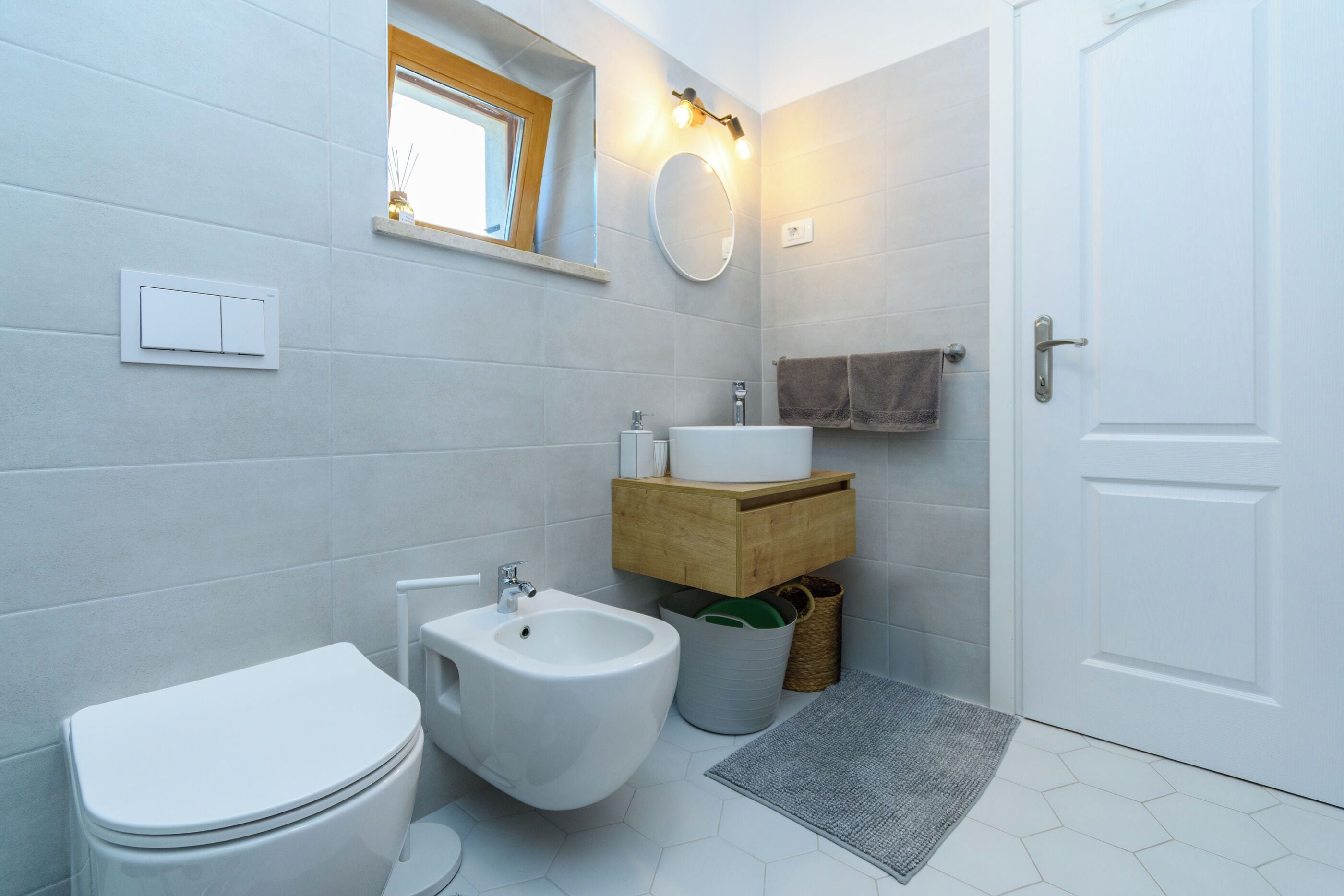 Une salle de bain moderne équipée de toilettes, d’un bidet, d’un lavabo et d’un miroir.