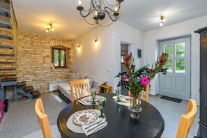 A dining area with a stone wall, a wooden staircase, and a view of the outdoors.