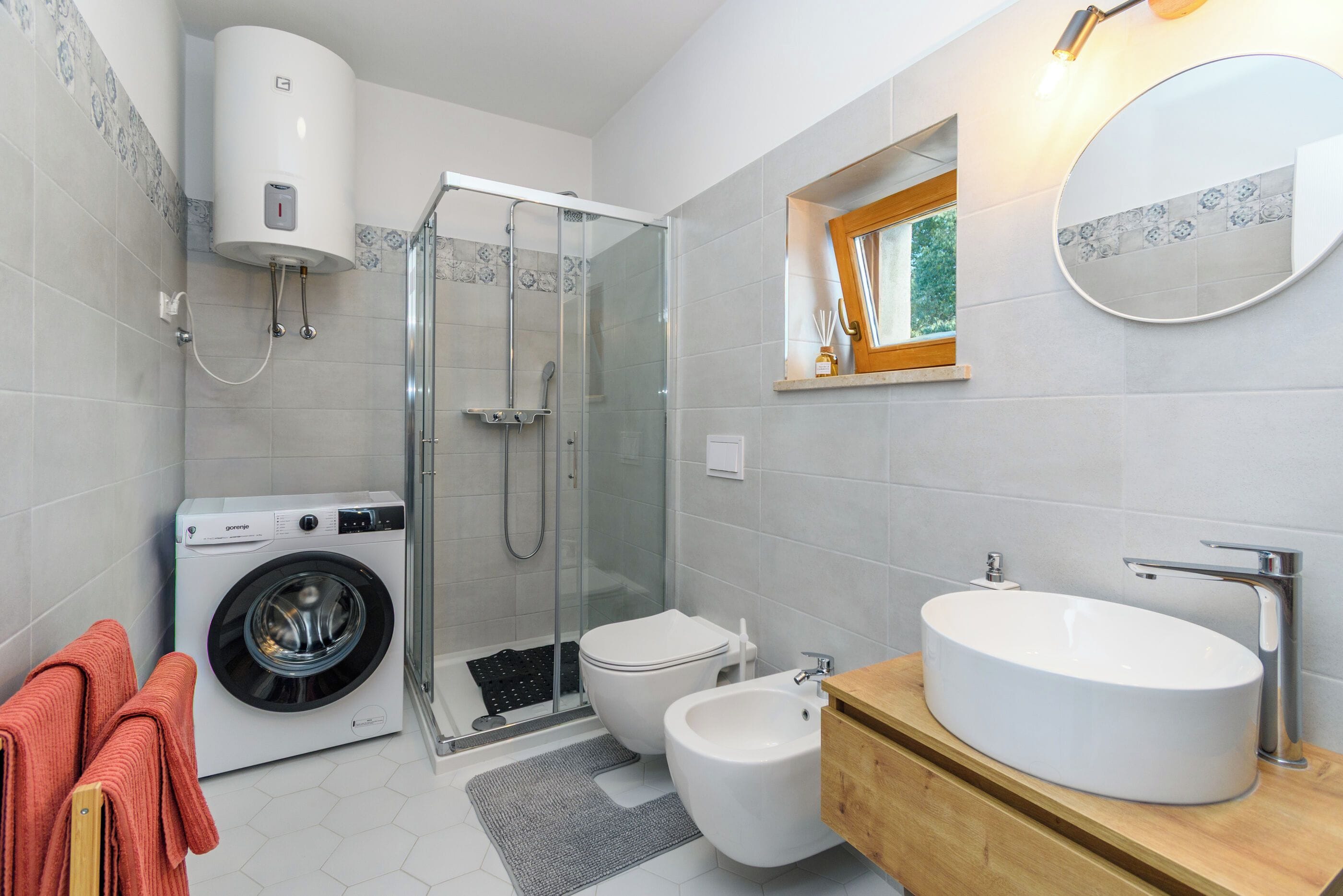 Ein modernes Badezimmer mit Waschmaschine, Toilette, Bidet und einem großen Waschbecken.