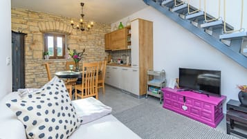 En hyggelig opholdsstue med sofa, spisebord og et køkken i baggrunden.
