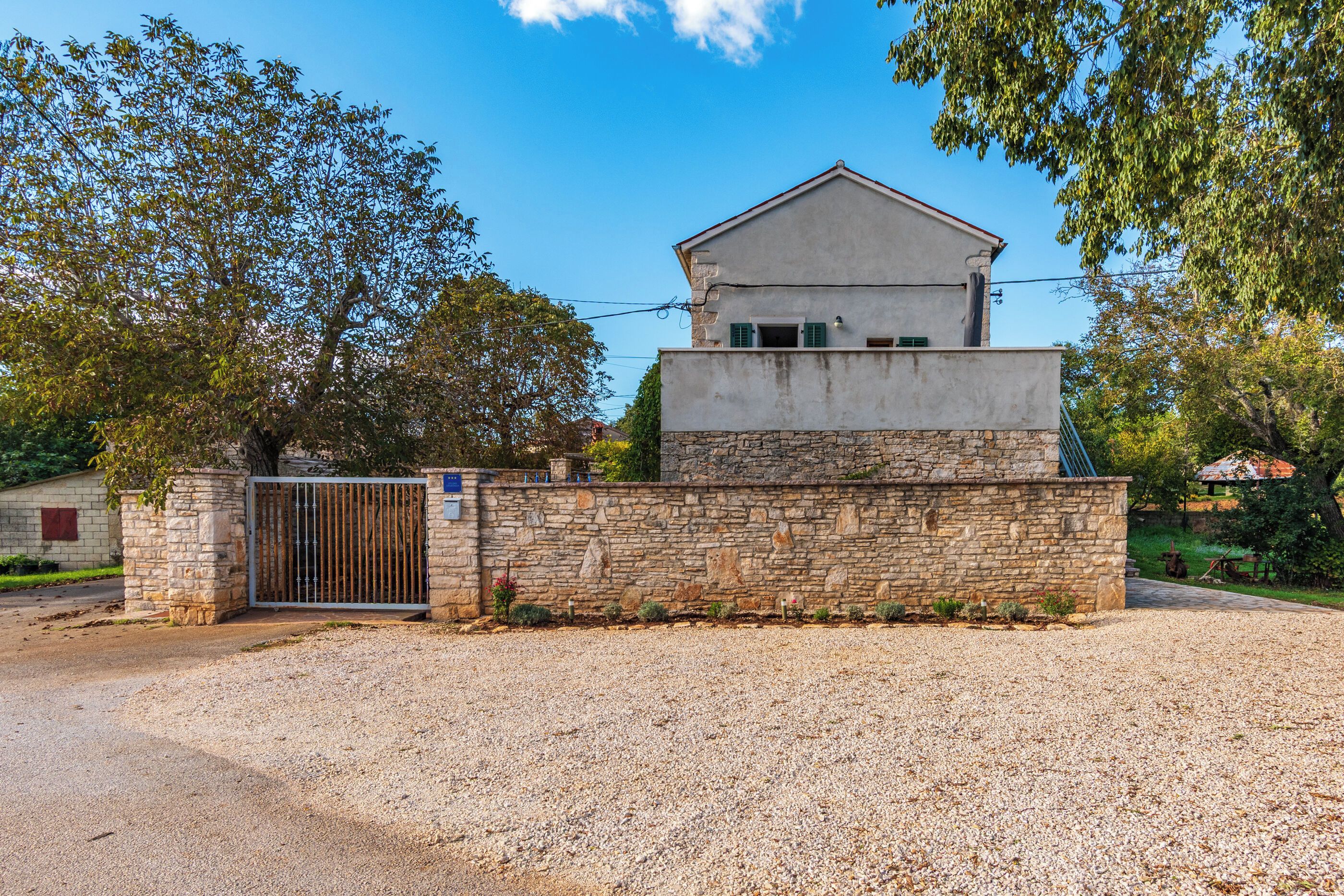 A two-story building with a stone wall and a metal gate.