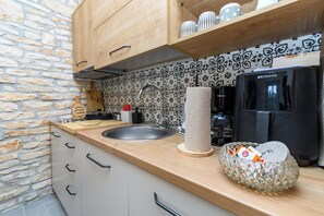 A kitchen with a stone wall, a sink, a coffee machine, and a patterned backsplash.