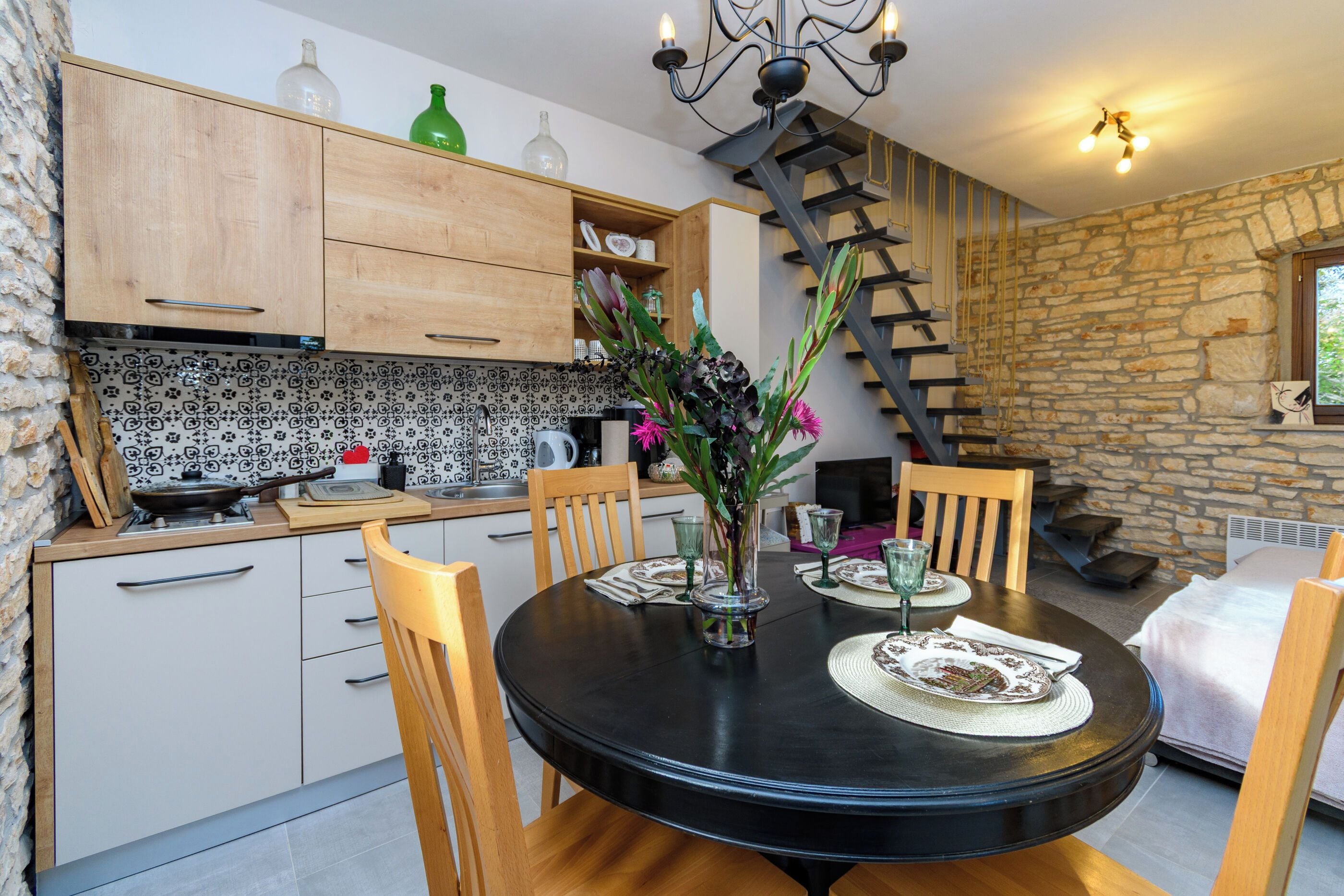 A dining area with a round table, chairs, and a vase with flowers.