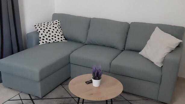 A modern living room with a grey sectional sofa, a round wooden coffee table, and a small potted plant. - House House Marijan (Karlobag)