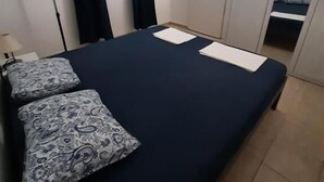A bedroom with a bed, a window with curtains, a wardrobe, and a bedside table. - House House Marijan (Karlobag)