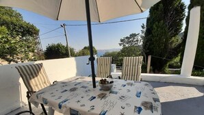 An outdoor seating area with a table and chairs, a bowl of fruit, and a view of the landscape. - House House Marijan (Karlobag)