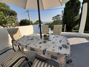 An outdoor seating area with a table and chairs, a bowl of fruit, and a view of the landscape. - House House Marijan (Karlobag)