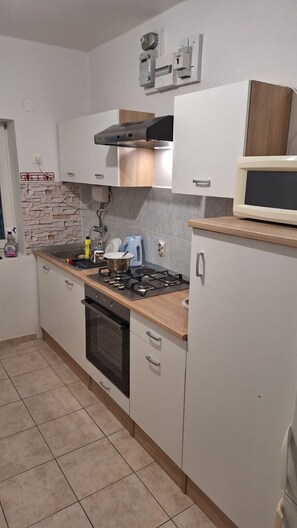 A kitchen with a stove, oven, microwave, and cabinets. - House House Marijan (Karlobag)