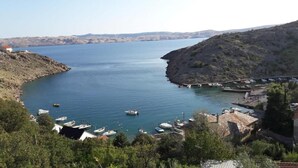 A coastal view with boats docked, a pier, and buildings along the shoreline. - House House Marijan (Karlobag)