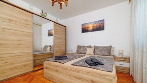 Un dormitorio con cama de madera, un espejo grande, una mesita de noche y un cuadro en la pared.