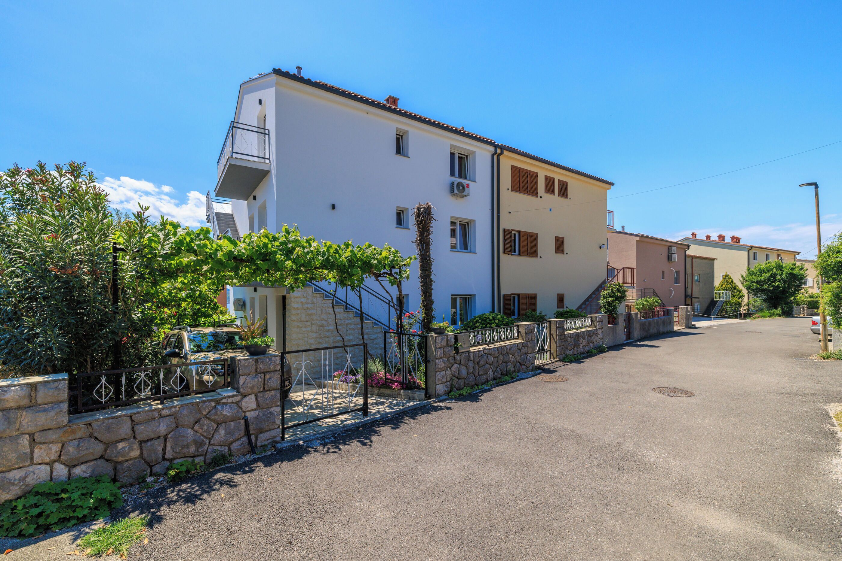 A residential building with a stone wall, a metal gate, and a clear sky.