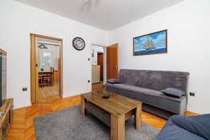 Una sala de estar con un sofá, una mesa de centro, un reloj y un cuadro en la pared.