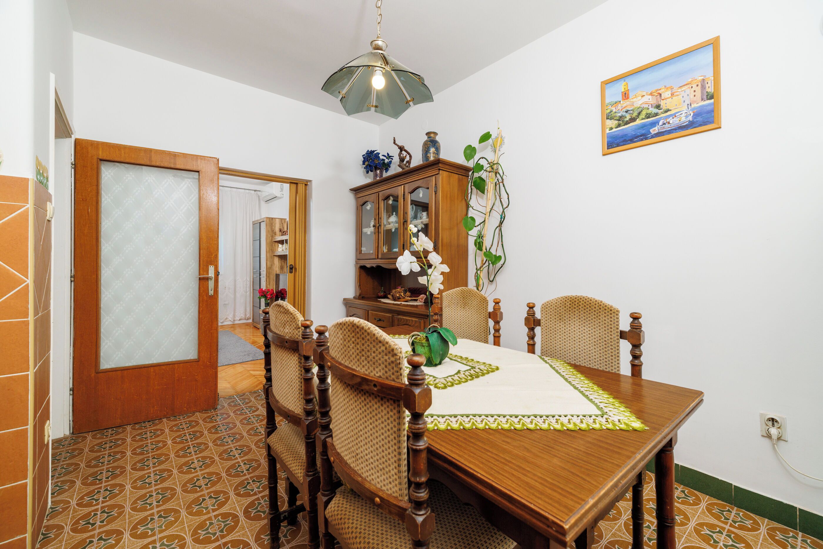 Zona pranzo con tavolo in legno, sedie, un armadio e un quadro appeso al muro.