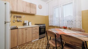 Una cocina con armarios de madera, una estufa y una mesa de comedor con sillas.