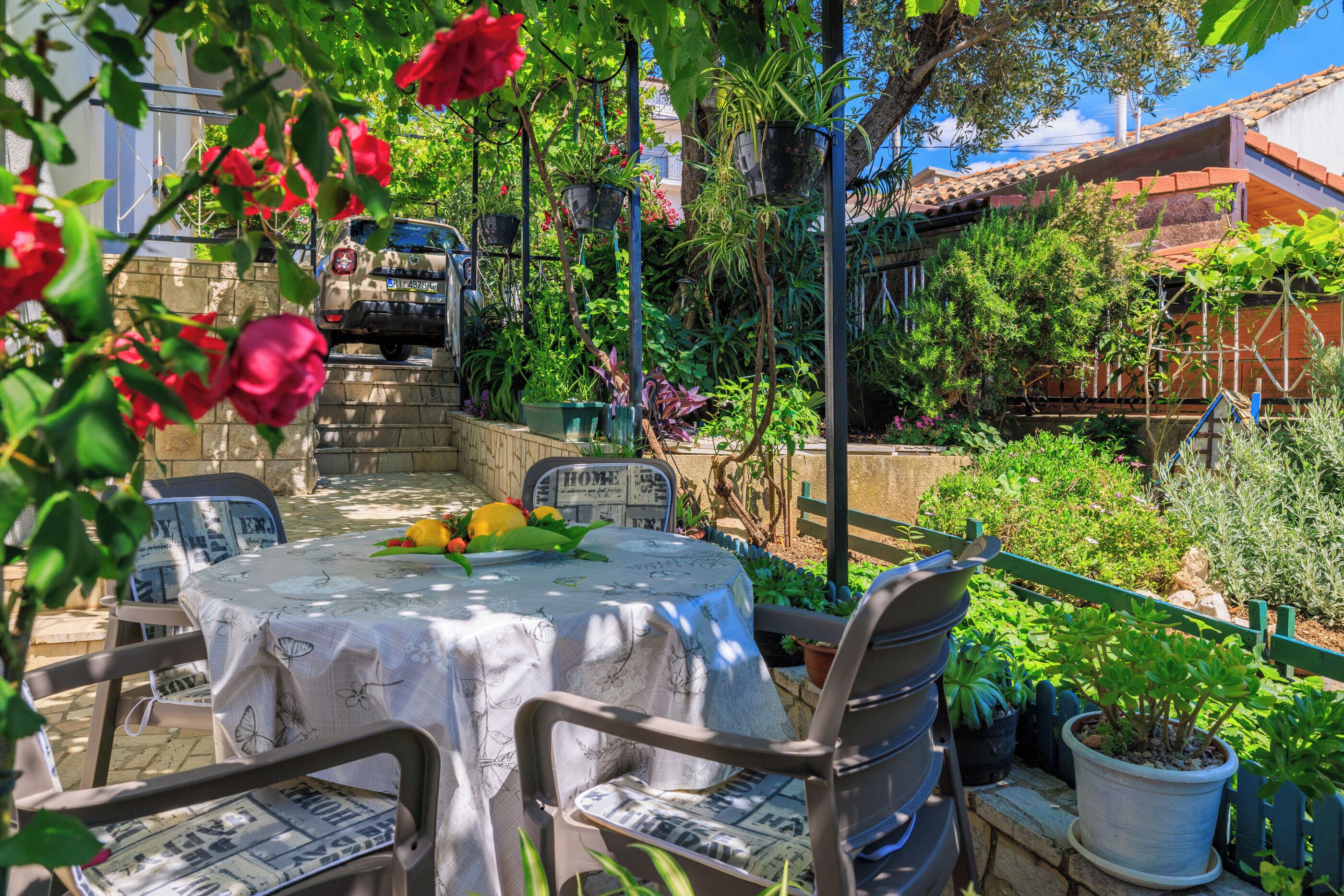A patio with a table and chairs, surrounded by potted plants and a stone wall.