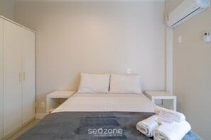 Ein Hotelzimmer mit Bett, Nachttisch, Kleiderschrank und Klimaanlage.