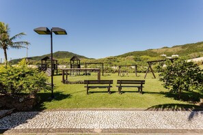 A park with wooden benches, a pergola, and a paved walkway. - Beachfront Apt in Full-service Condominium Rit206 (Florianópolis)