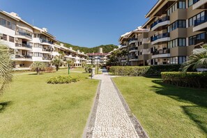 Ein mehrstöckiges Hotel mit Balkonen, einem gepflasterten Weg und angelegten Gärten.