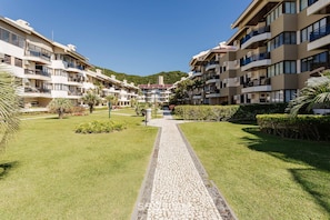 A multi-story hotel with balconies, a paved walkway, and landscaped gardens. - Beachfront Apt in Full-service Condominium Rit206 (Florianópolis)