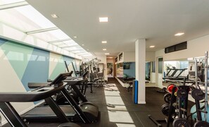 Ein Fitnessstudio mit Laufbändern, Kraftgeräten und Kurzhanteln.