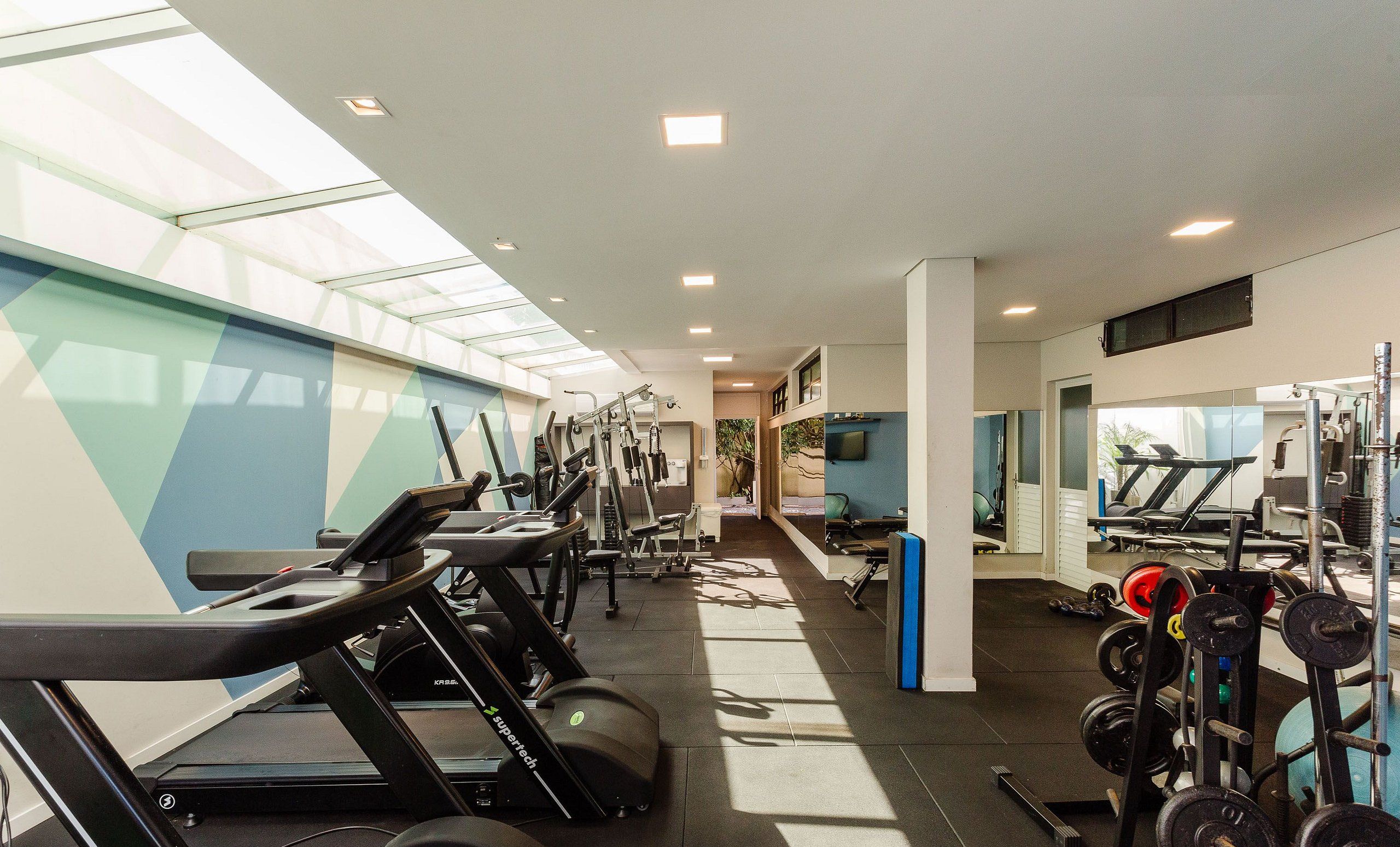 Une salle de sport équipée de tapis de course, d’appareils de musculation et de poids libres.