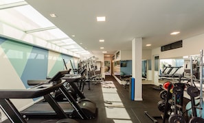 Et fitnesscenter med løbebånd, styrkemaskiner og håndvægte.