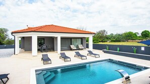 A swimming pool with lounge chairs, a covered seating area, and a view of the surrounding landscape. - House Nadalina (Vrsi)