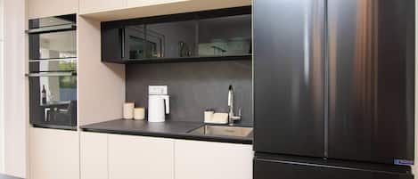 A modern kitchen with a stainless steel refrigerator, a built-in oven, and a dishwasher.
