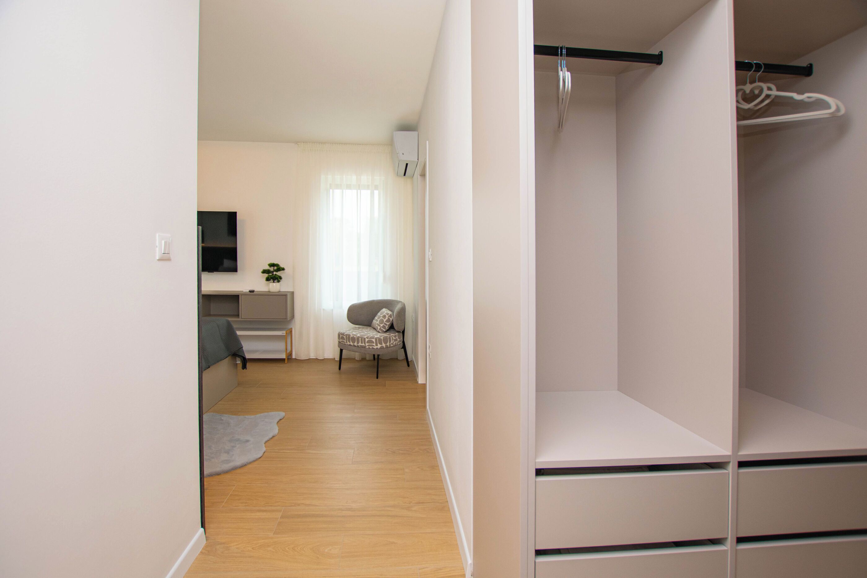 A room with a bed, a desk, a chair, and a closet with hanging space.