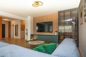 Ein modernes Wohnzimmer mit Flachbildfernseher, rundem Couchtisch und einer Couch.