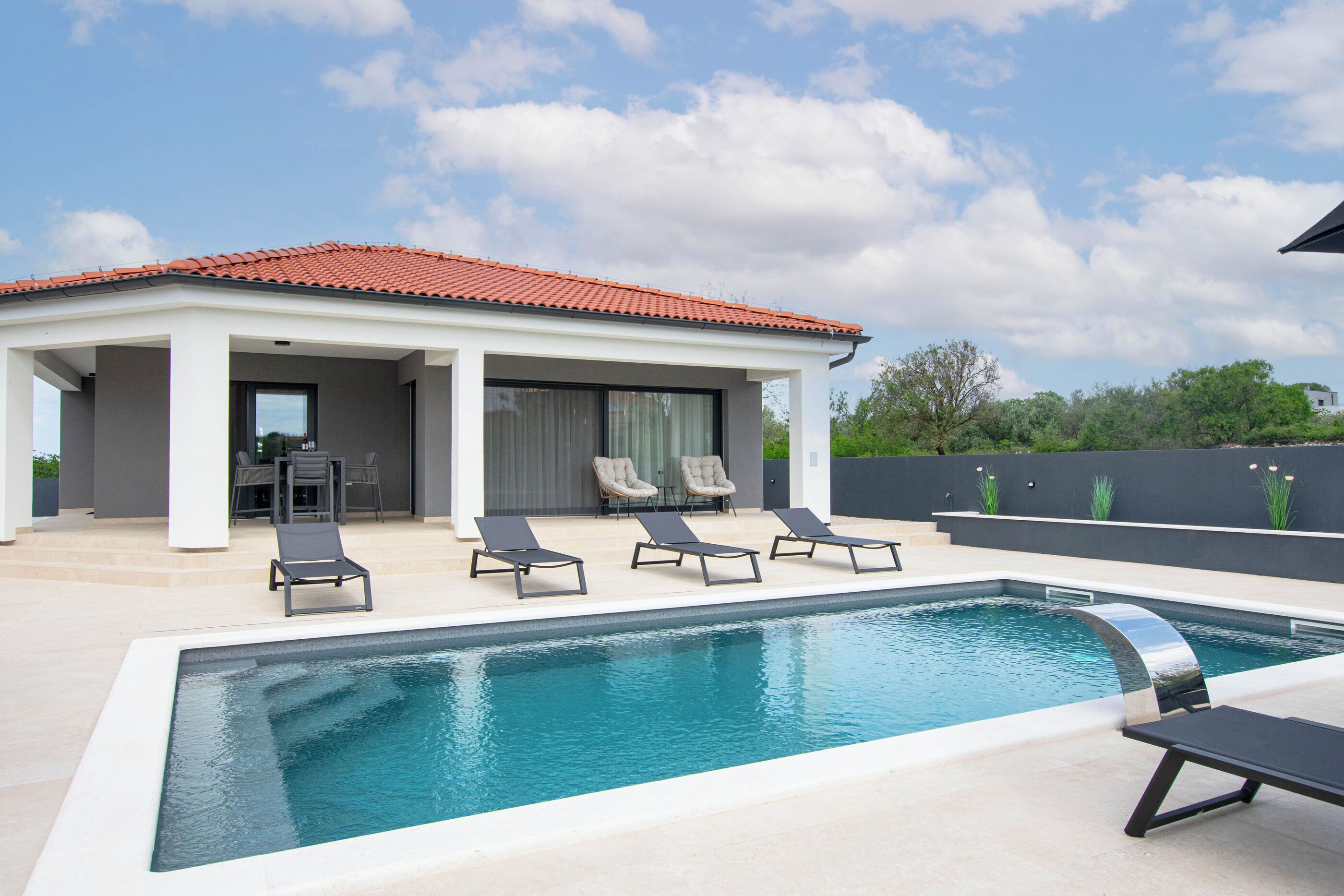 A modern pool area with lounge chairs and a covered patio.
