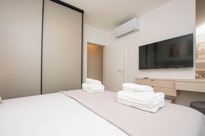 Ein Hotelzimmer mit Bett, Fernseher, Schreibtisch und Kleiderschrank.