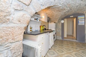 A kitchen with stone walls, a built-in oven, and a tiled floor. - Apartment D and D (Punat)