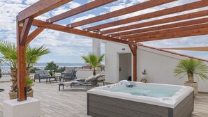 A rooftop terrace with a hot tub, lounge chairs, and potted plants. - Apartment Azure Pine (Okrug)