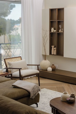 Una sala de estar moderna con un sofá, una silla, una mesa de centro y un estante con objetos decorativos.