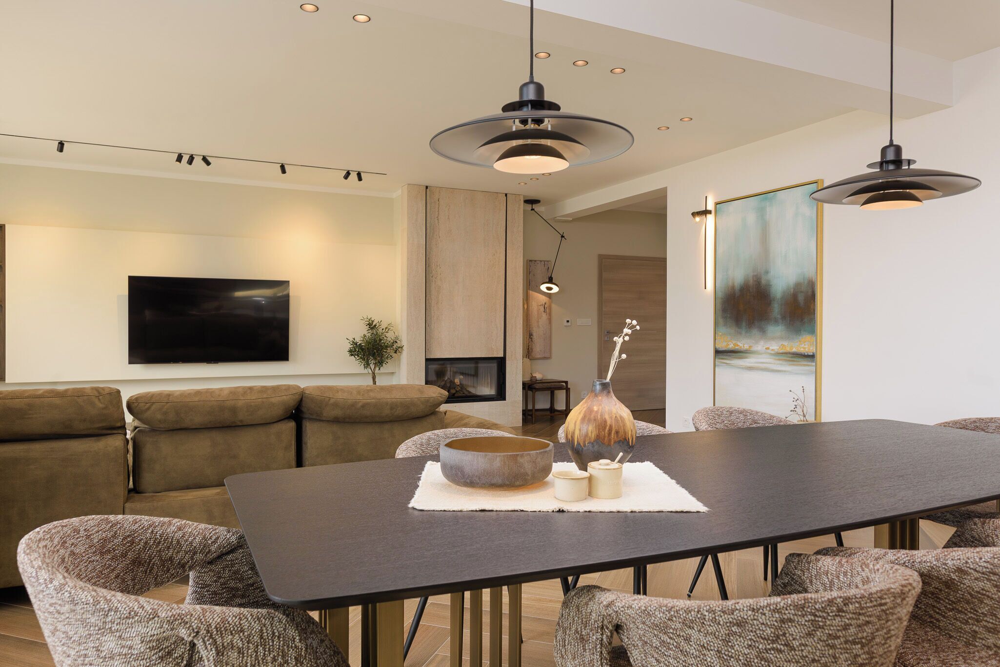 Een moderne woonkamer met een bank, een eettafel en hanglampen.