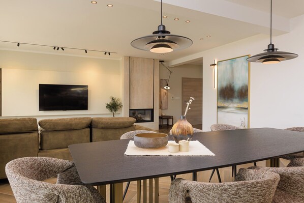 Una sala de estar moderna con un sofá, una mesa de comedor e iluminación colgante.