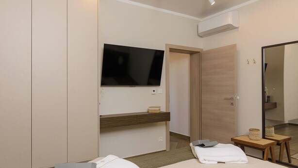 A hotel room with a bed, a flat-screen TV mounted on the wall, a wooden door, and a small table with a basket. - Apartment Azure Pine (Okrug)