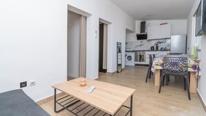 A modern apartment with a kitchen, dining area, and a small table with a remote control. - Apartment Panorama Nicolas (Kastela)