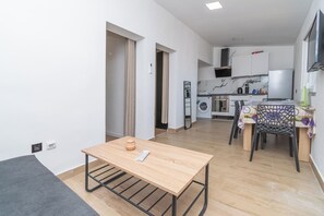 A modern apartment with a kitchen, dining area, and a small table with a remote control. - Apartment Panorama Nicolas (Kastela)