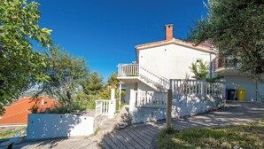 A two-story building with a balcony, a staircase leading to the entrance, and a view of the surrounding greenery. - Apartment Panorama Nicolas (Kastela)