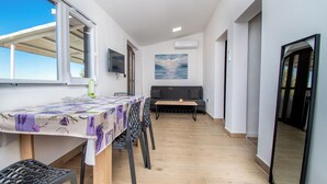 A dining area with a table, chairs, a sofa, and a painting on the wall. - Apartment Panorama Nicolas (Kastela)