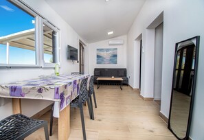 A dining area with a table, chairs, a sofa, and a painting on the wall. - Apartment Panorama Nicolas (Kastela)