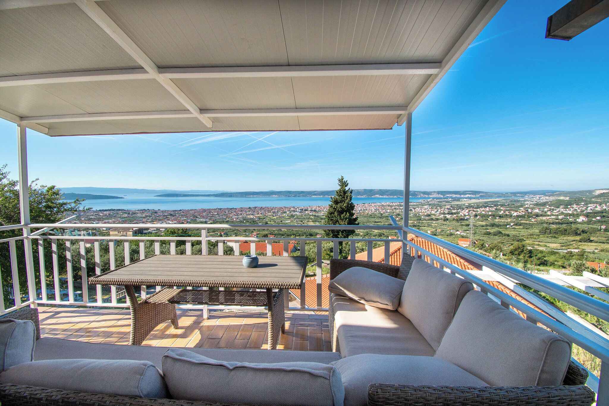 A covered outdoor seating area with a table and chairs, overlooking a scenic landscape.