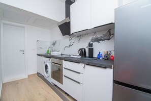 A compact kitchen with a washing machine, a coffee maker, and a refrigerator. - Apartment Panorama Nicolas (Kastela)